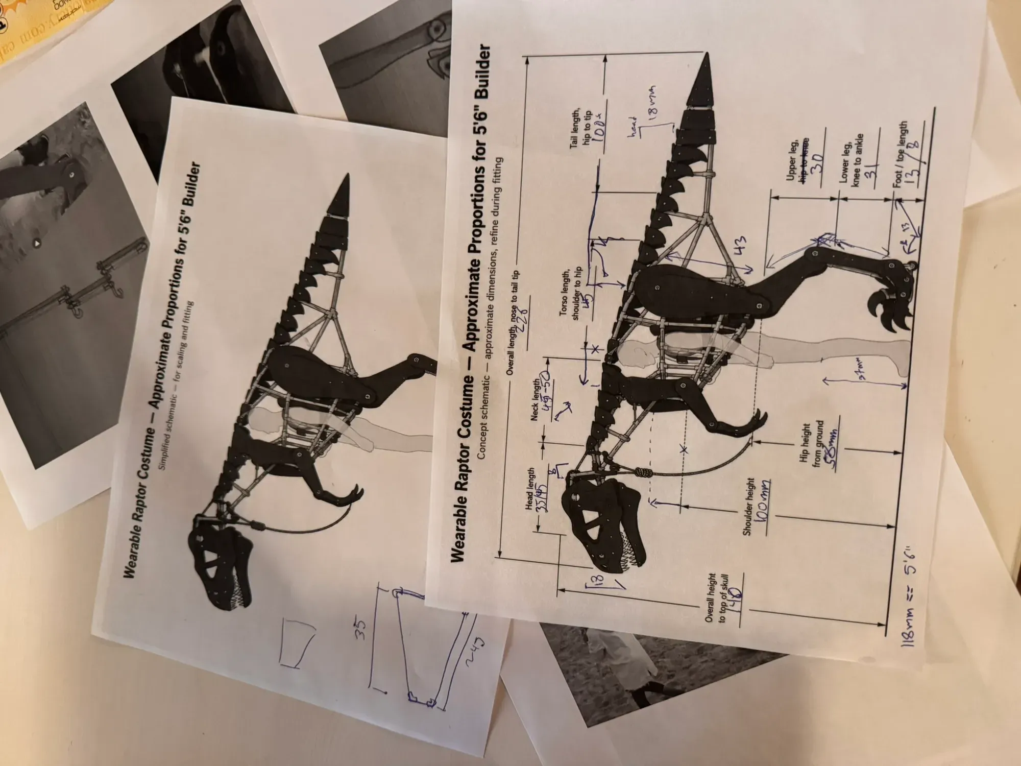 Printed raptor proportion schematics stacked on the desk, covered in handwritten dimensions