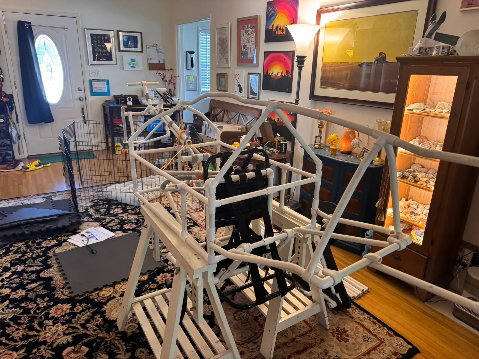 The torso cage and tail truss from behind, harness hanging in the middle, sawhorses doing the creature’s standing for it